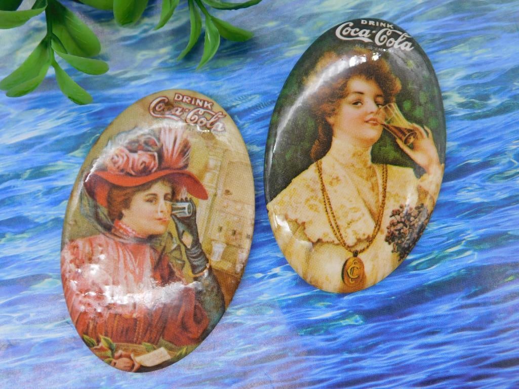 Vintage Coca-Cola Pocket Mirrors: - Pair of vintage Coca-Cola-themed pocket mirrors. | - Features iconic Coca-Cola advertisements with vintage-style illustrations. | - One mirror shows a woman with a red hat holding a Coca-Cola bottle