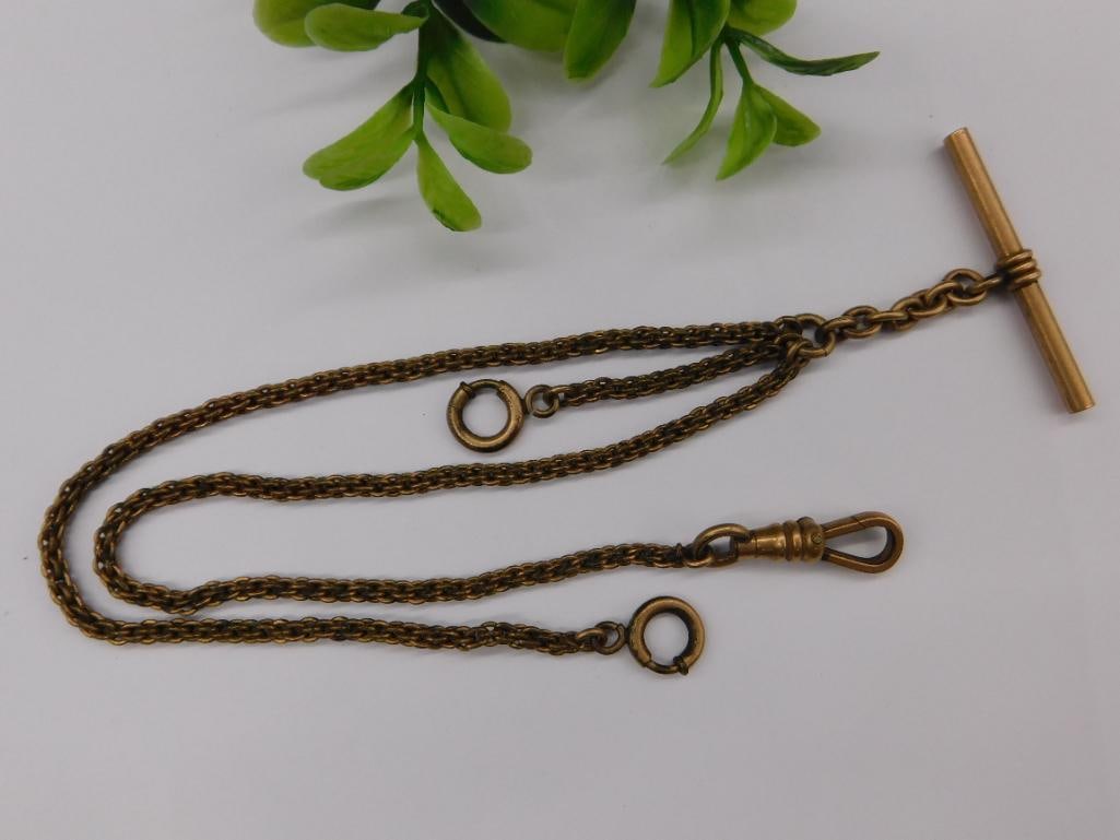 Antique Gold-Toned Pocket Watch Chain with T-Bar: - Antique gold-toned pocket watch chain. | - Features a T-bar at one end and a swivel clasp at the other. | - Includes two additional circular attachments for added functionality. | - Dual-chain desig