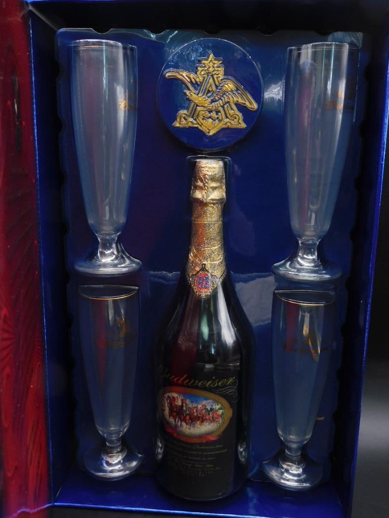 Budweiser Gift Set With Glasses and Bottle Stopper: Complete Budweiser gift set featuring a decorative box, a bottle of Budweiser, four champagne-style glasses, and a detailed bottle stopper displaying the iconic Budweiser logo and emblem. The packagin