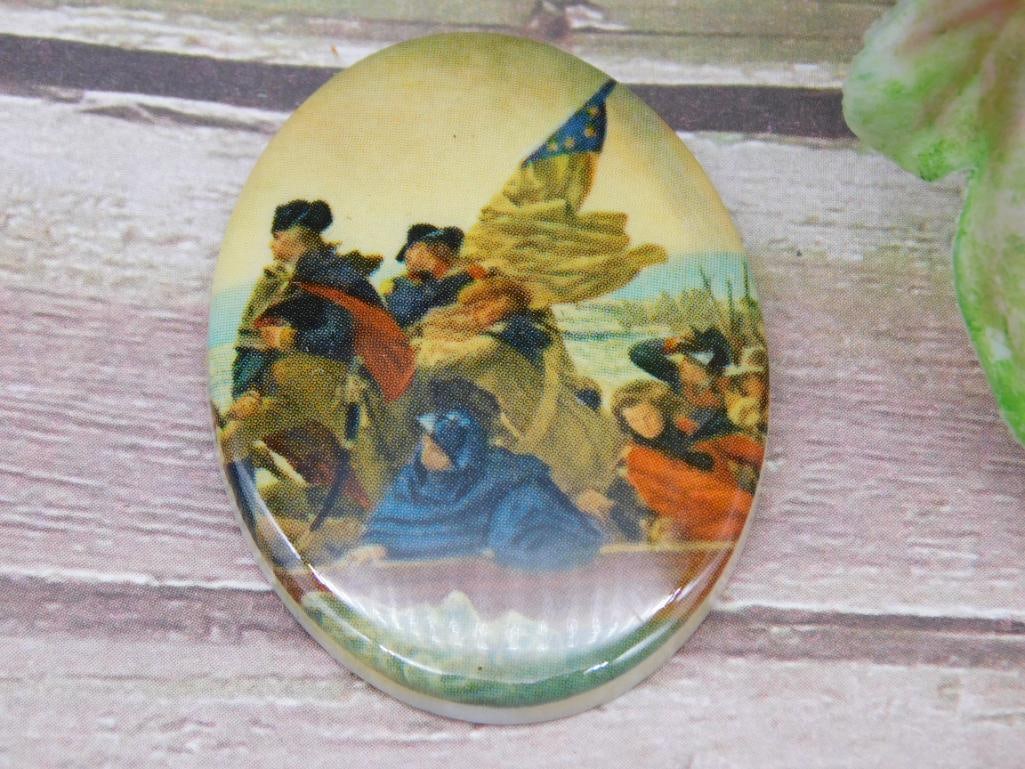 Oval Pendant Featuring Historic Crossing Scene Design: Oval-shaped pendant displaying a detailed historic scene, possibly depicting a crossing or religious moment. The colorful design appears encased beneath a glossy surface. A measuring ruler is used for