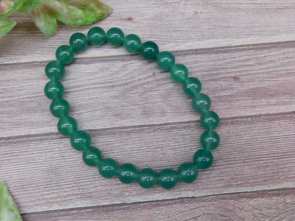 Green Beaded Stretch Bracelet with Round Beads: Green beaded stretch bracelet featuring round, uniform beads with a polished finish. Elastic cord construction provides a comfortable, flexible fit. Appears to be suitable as a unisex accessory. Measu