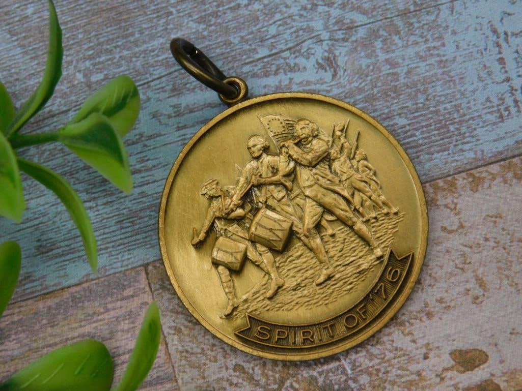 Spirit of ?76 Gold-Tone Medallion Pendant: Gold-tone medallion pendant featuring the iconic 'Spirit of 76' design on one side and commemorative 'United States of America 1776-1976' on the other. Includes a loop for easy attachm