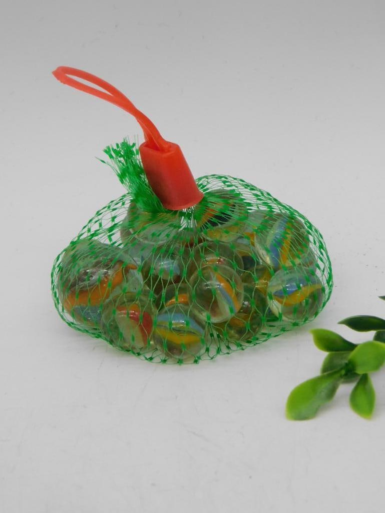 Bag of Decorative Glass Marbles in Green Mesh: Bag of decorative glass marbles contained in a green mesh with an orange closure loop. Each marble features a colorful design. The mesh bag is securely tied, keeping the marbles together. Lot labeled 