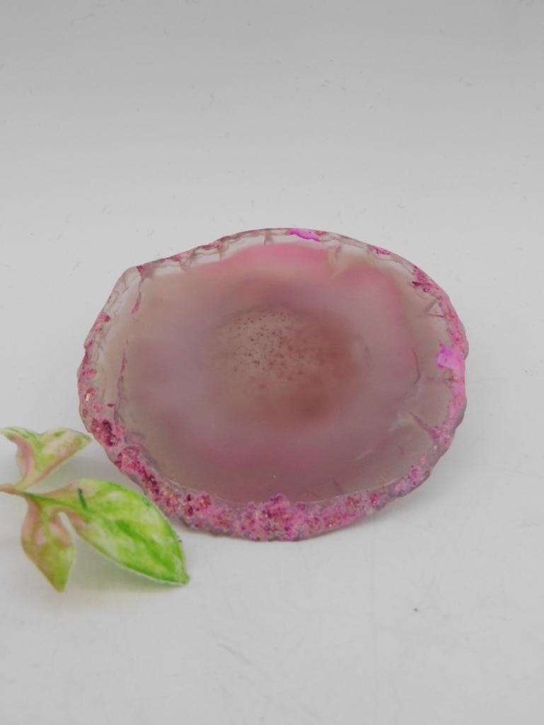 Pink Agate Geode Slice Display Piece ROCK STONE LAPIDARY SPECIMEN: A pink agate geode slice with natural crystal formations in the center, polished to a smooth, glossy finish on both sides. Features vibrant pink edges and a translucent central area. Small plant and a