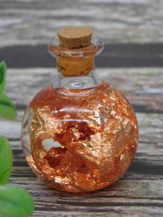 Small Glass Bottle With Real Copper Flakes Rock Stone Lapidary Specimen: This lot features a small round glass bottle with a cork stopper. The bottle is decorated with real copper flakes. It is shown with a ruler for reference, indicating its small size. The listed weight