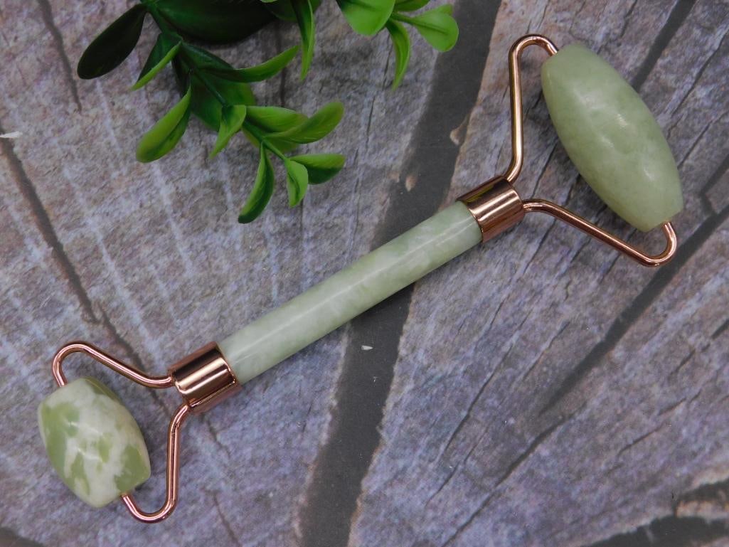 Dual-Ended Jade Facial Roller with Rose Gold Accents: This jade facial roller features dual ends with a larger and smaller roller for versatile use. It is crafted from green jade stone with polished rose gold-tone metal detailing. Measuring approximately