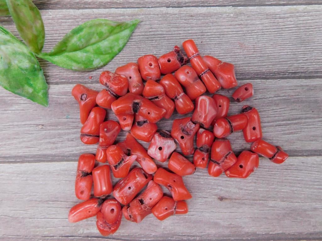 Lot of Red Coral Beads with Approximate Weight: This listing features a collection of red coral beads. The beads show natural variations in shape, size, and coloring. Many of the beads include pre-drilled holes, making them suitable for stringing p