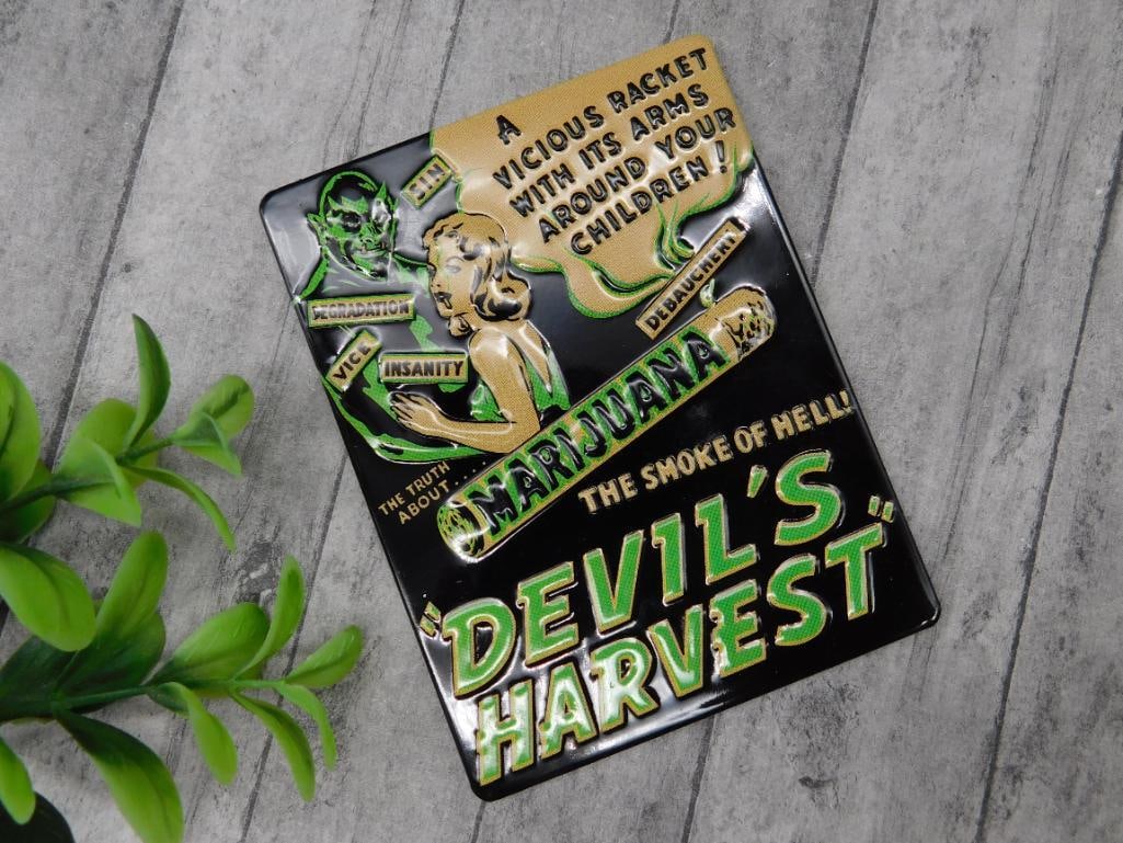 Devil?s Harvest Metal Sign with Vintage Design: Metal sign featuring a design inspired by vintage-style marijuana propaganda, with the text "Devil's Harvest: The Smoke of Hell." Includes bold graphics and striking typography. A ruler included in th