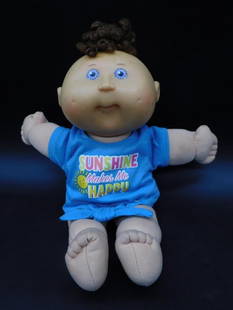 2004 OAA Inc. Play Along Doll with Sunshine Outfit: This 2004 OAA Inc. Play Along doll features a soft body, a vinyl head, and fabric blue shirt with 'Sunshine Makes Me Happy' print. It includes manufacturer's tags and green signature on the doll's bod