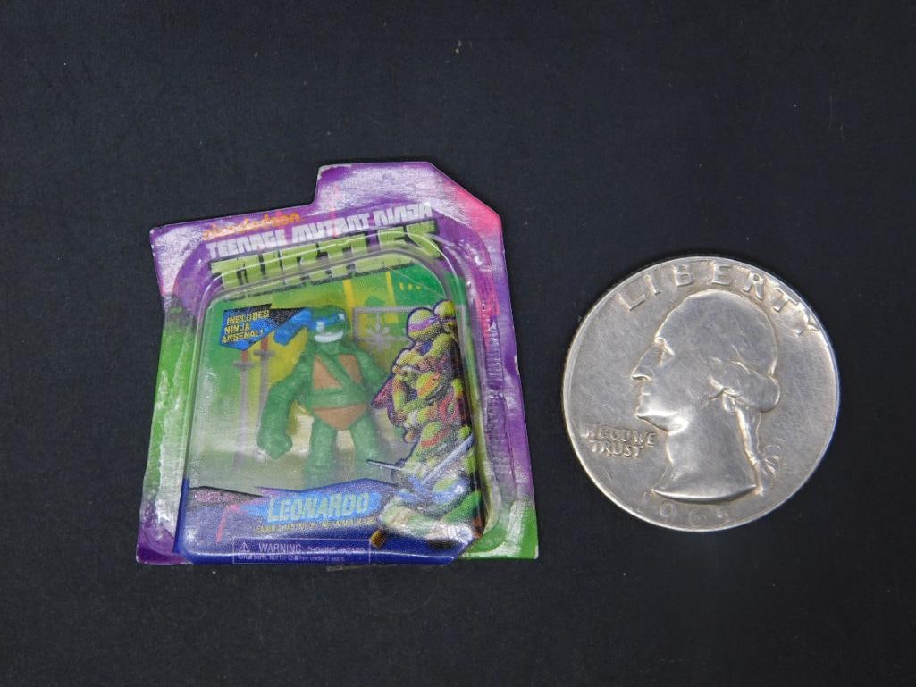 Mini Brand Teenage Mutant Ninja Turtles Mini Leonardo Figure: Miniature Teenage Mutant Ninja Turtles Leonardo figure still in its original packaging. Features Leonardo, the sword-wielding turtle, with green and purple-colored backing card. Packaging shows some s
