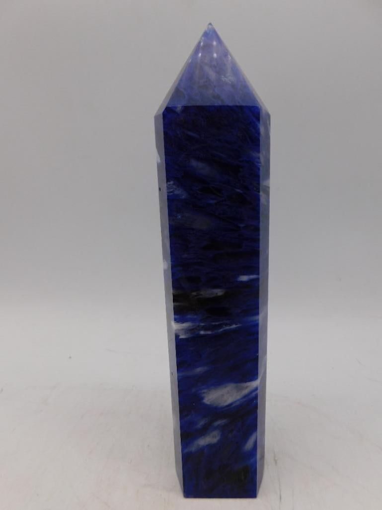 Blue Stone Obelisk Tower with Pointed Ends Rock Stone Lapidary Specimen: Polished obelisk-shaped tower crafted from a blue stone material. | - Features a deep blue color with lighter and darker streaks for a textured effect. | - Ends are pointed, creating a tapered, symmet