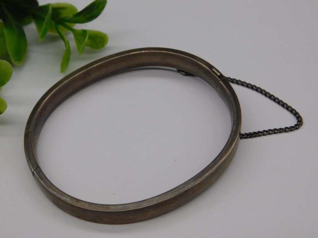 Vintage Sterling Silver Bracelet with Safety Chain: - Vintage bracelet crafted from sterling silver. | - Features an engraved marking 'Sterling Tiffany' inside the band. | - Comes with a safety chain to enhance security when worn. | - Oval-shaped desig