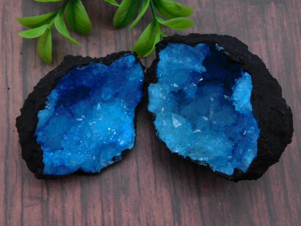 Vivid Blue Geode Split in Two Halves Rock Stone Lapidary Specimen: Natural geode cluster showcasing bright blue crystal formations inside. | Split into two halves, displaying internal crystalline structures. | Black outer shell provides contrast to vibrant interior.