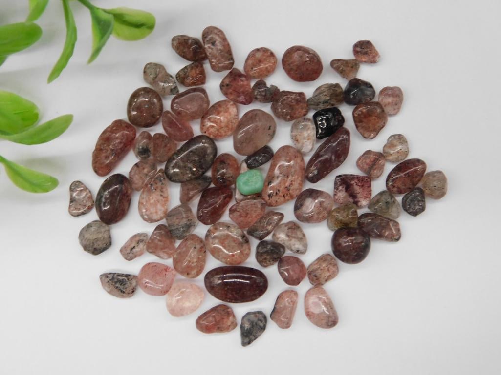 20 Grams of Strawberry Quartz Gemstones Rock Stone Lapidary Specimen: - Collection of tumbled strawberry quartz stones. | - Total weight of 20 grams, as indicated on the label. | - Various shapes and shades of pink to reddish hues. | - Coin in the image for scale