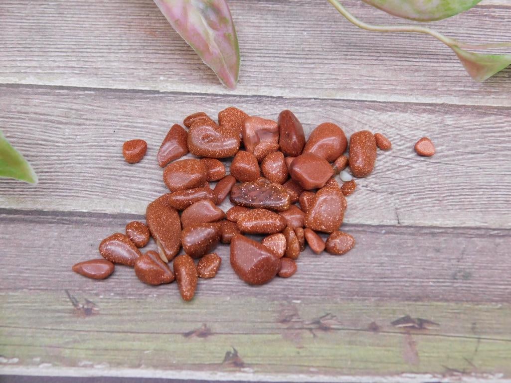 12 Grams of Goldstone Gemstones: This lot includes 12 grams of gold sandstone gemstones. The stones exhibit a shimmering appearance with varying sizes and shapes. Ideal for collectors or decorative projects.