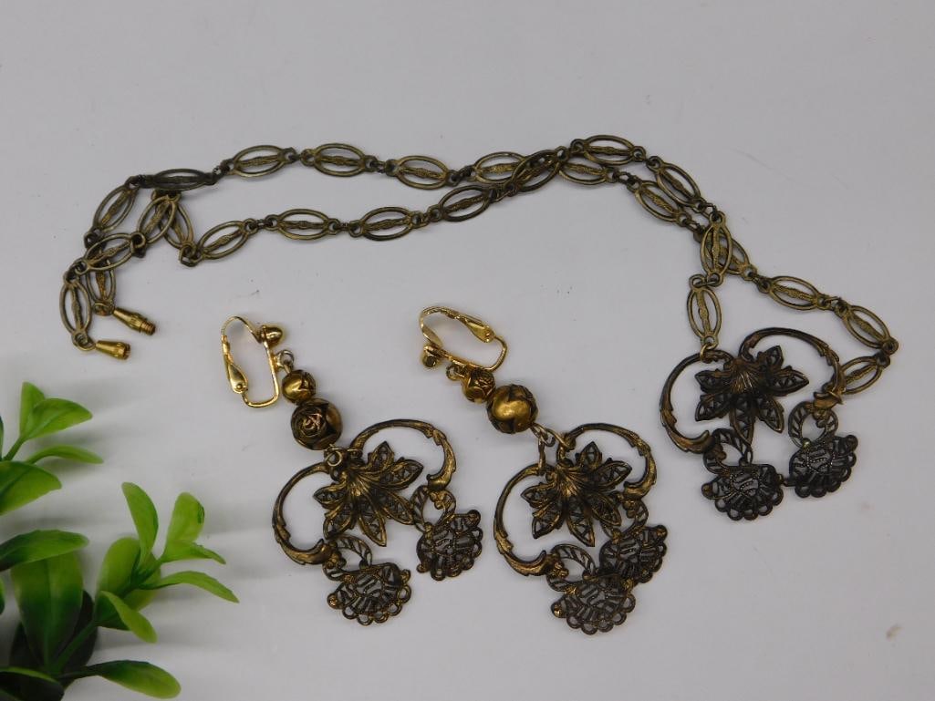 Antique-Style Necklace and Earring Set in Bronze Tones: - A jewelry set featuring a necklace and a pair of matching earrings in bronze tones. | - Necklace includes an ornate chain with connecting links and an intricate pendant design. | - Earrings feature
