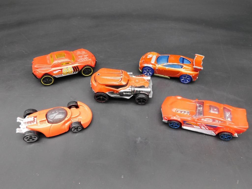 Lot of 5 Red Hot Wheels Cars with Various Designs: This auction features a lot of 5 Hot Wheels cars, all in red with varying designs and production years. The collection includes cars made in Malaysia, Indonesia, and China with visible branding like '