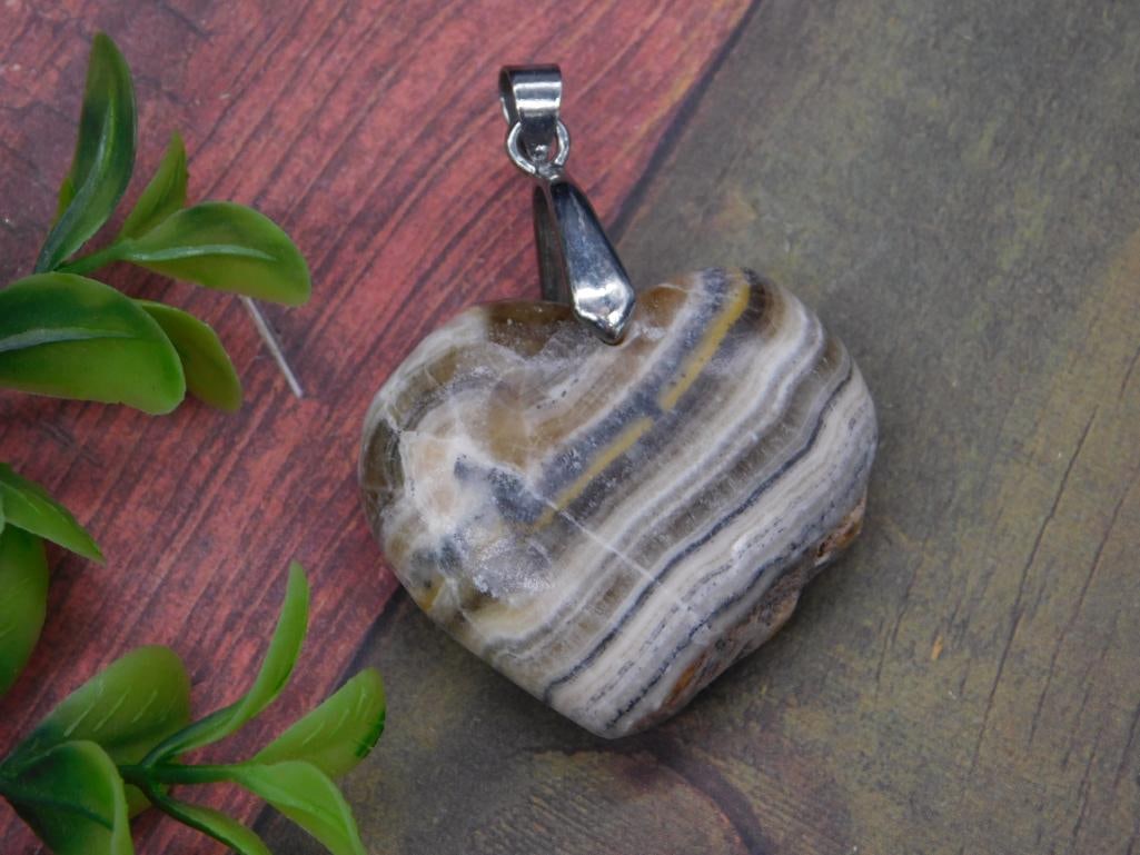 BANDED CALCITE HEART PENDANT ROCK STONE LAPIDARY SPECIMEN: BANDED CALCITE HEART PENDANT ROCK STONE LAPIDARY SPECIMEN — Part of our Discover Vintage Vault, Crystals and Gems auction at HATMAN'S Auctions! Please see photos for measurements and condition.