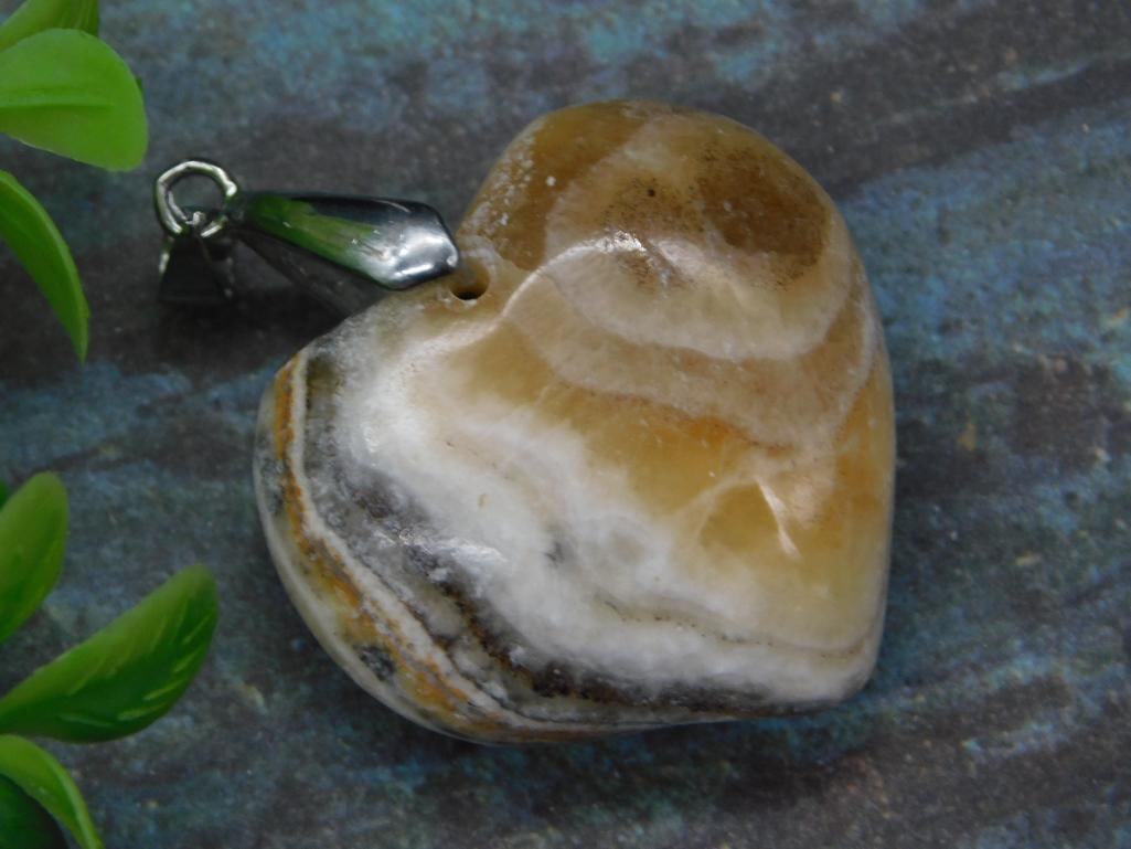 BANDED CALCITE HEART PENDANT ROCK STONE LAPIDARY SPECIMEN: BANDED CALCITE HEART PENDANT ROCK STONE LAPIDARY SPECIMEN — Part of our Discover Vintage Vault, Crystals and Gems auction at HATMAN'S Auctions! Please see photos for measurements and condition.