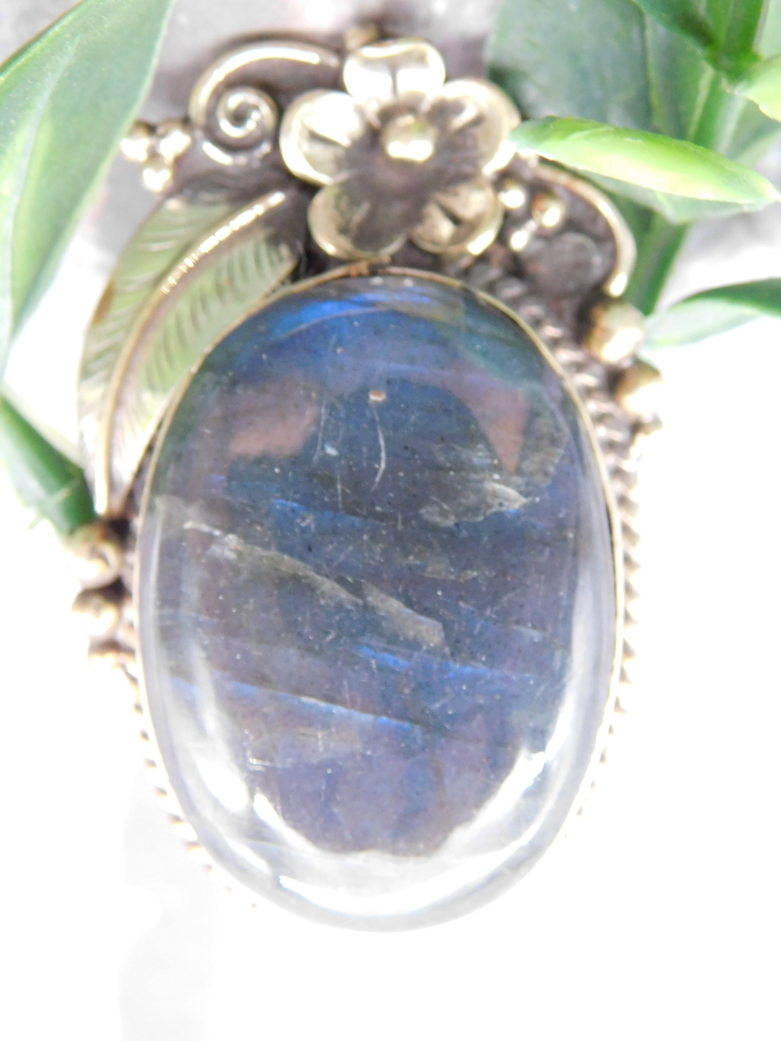 Pendant — Labradorite Statement Ring Flower Leaf Setting with Silver Engraved Wide Band Ring 31g: Two-piece jewelry lot: (1) A large oval labradorite or spectrolite cabochon pendant with deep blue-grey adularescence flash, set in an ornate silver setting with flower and leaf motifs and beaded bord