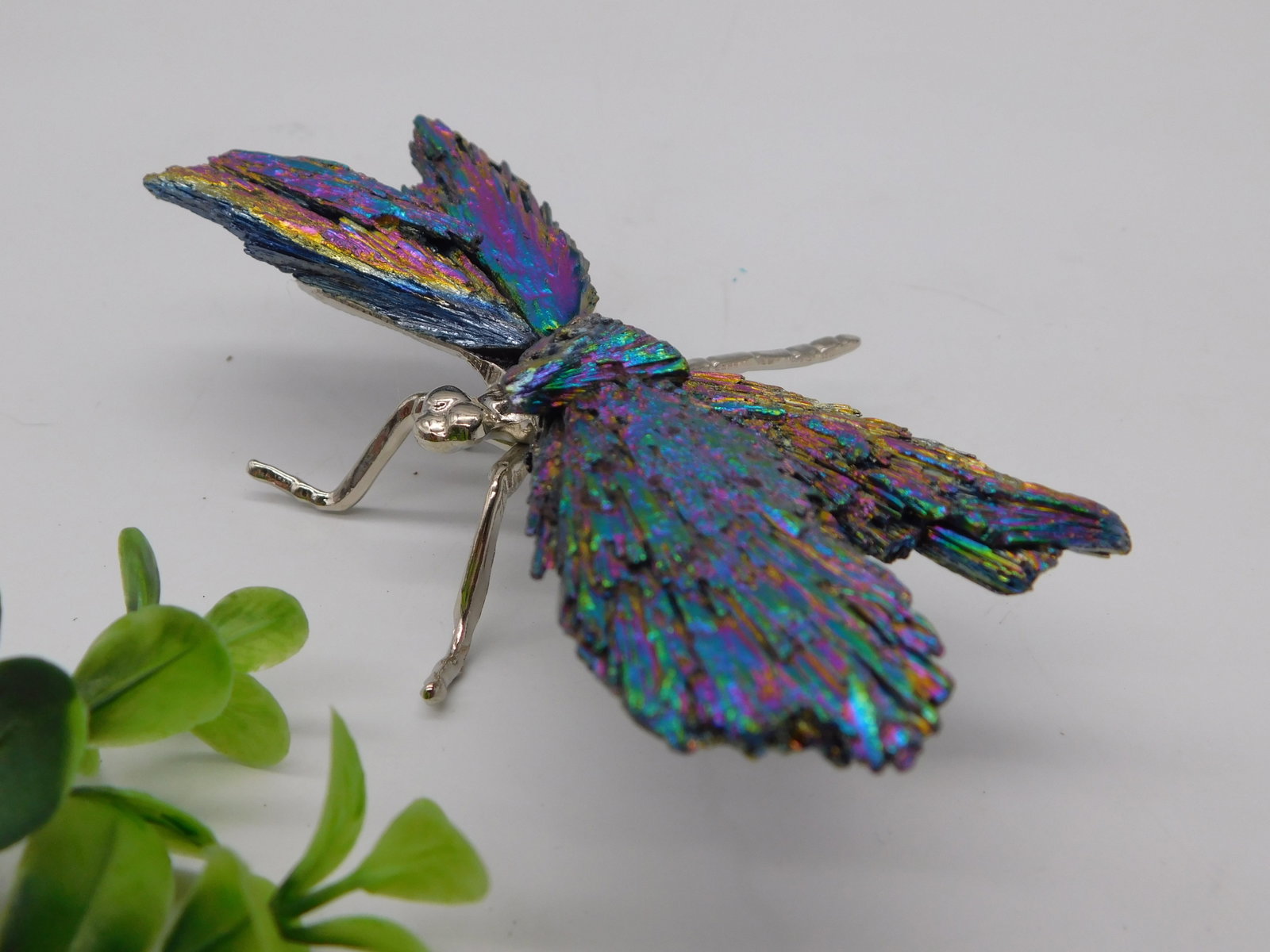 Crystal — Rainbow Titanium Aura Quartz Butterfly Figurine with Silver Metal Body: A stunning decorative butterfly sculpture with four wings made of rainbow titanium-coated druzy quartz, displaying vivid iridescent colors including purple, blue, green, and gold. The body, head, ante