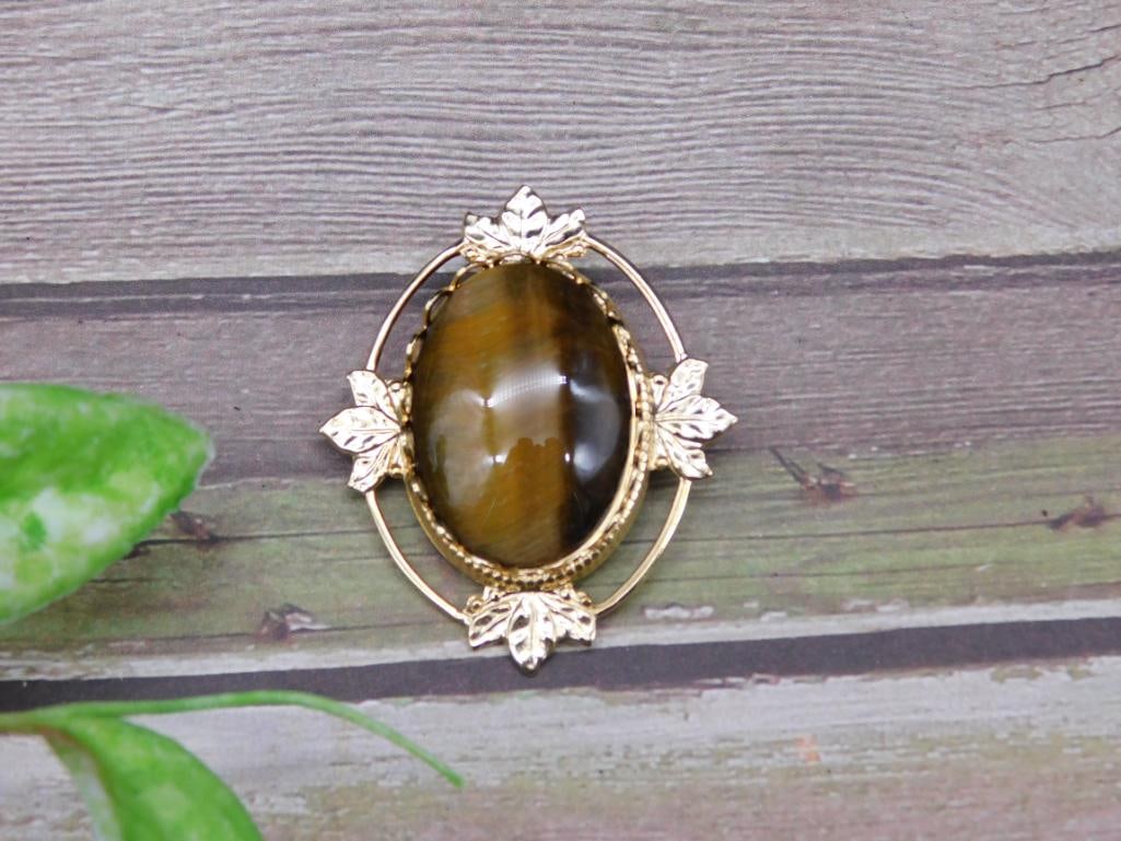 Gold-Tone Pin With Tiger?s Eye Stone and Leaf Accents: Gold-Tone Pin With Tiger?s Eye Stone and Leaf Accents - Part of our Discover Gilded Gallery, Crystals and Gems auction at HATMAN'S Auctions! Please see photos for measurements and condition. YES, we