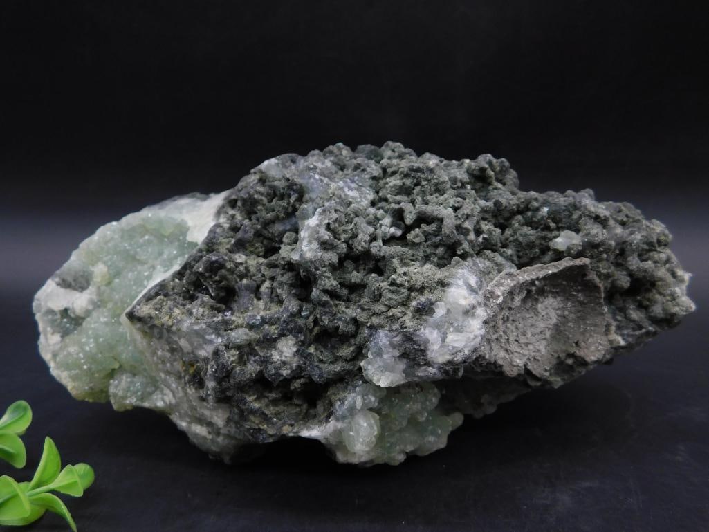 Phrenite Specimen Featuring Green Crystals and Black Matrix: Phrenite Specimen Featuring Green Crystals and Black Matrix - This mineral specimen showcases an array of green crystalline formations embedded within a black and gray matrix. Intricate textures and