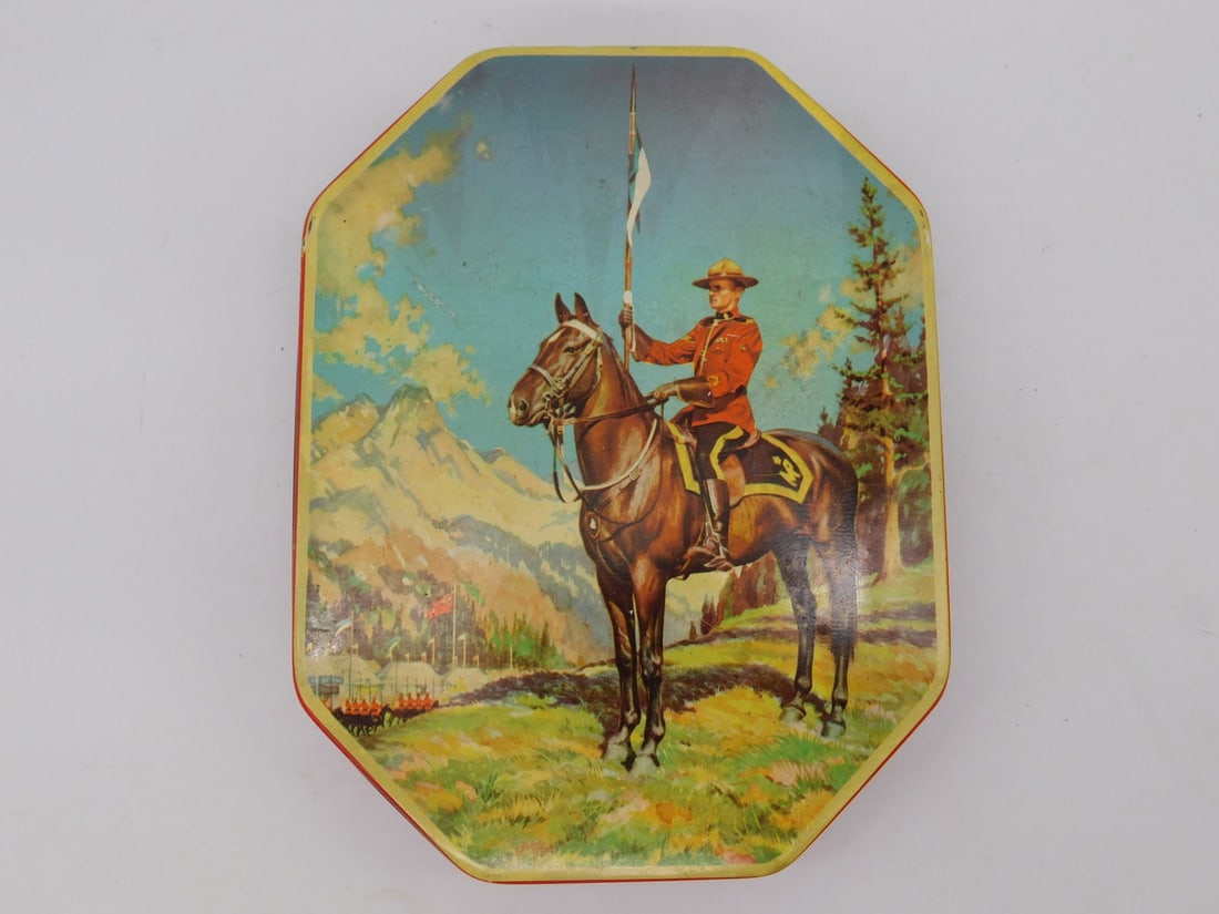 RCMP Mountie Tin with Two Rolls of Quarters: This colorful octagonal tin depicts a Royal Canadian Mounted Police officer on horseback holding a pennant, with a label identifying it as a Boy Blue Assortment of Toffees tin made in England by