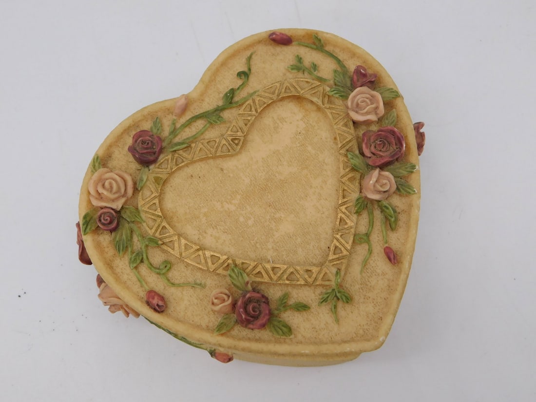 Heart-Shaped Rose-Decorated Trinket Box with Rolled Coin Set: This lot features a heart-shaped resin trinket/jewelry box in an ivory tone, its lid adorned with applied pink and cream roses, green vines, and a gold lattice border; the box is marked on the