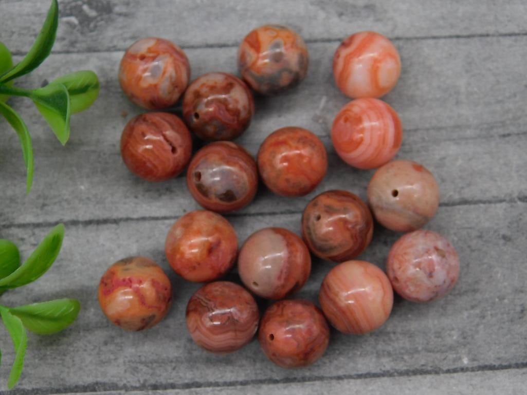 Collection of Pink and Red Banded Stone Beads: A lot of 15 spherical pink and red banded stone beads. Each bead features subtle variations in coloration, ranging from soft pinks to deep reddish tones, with natural banded patterns. The beads are