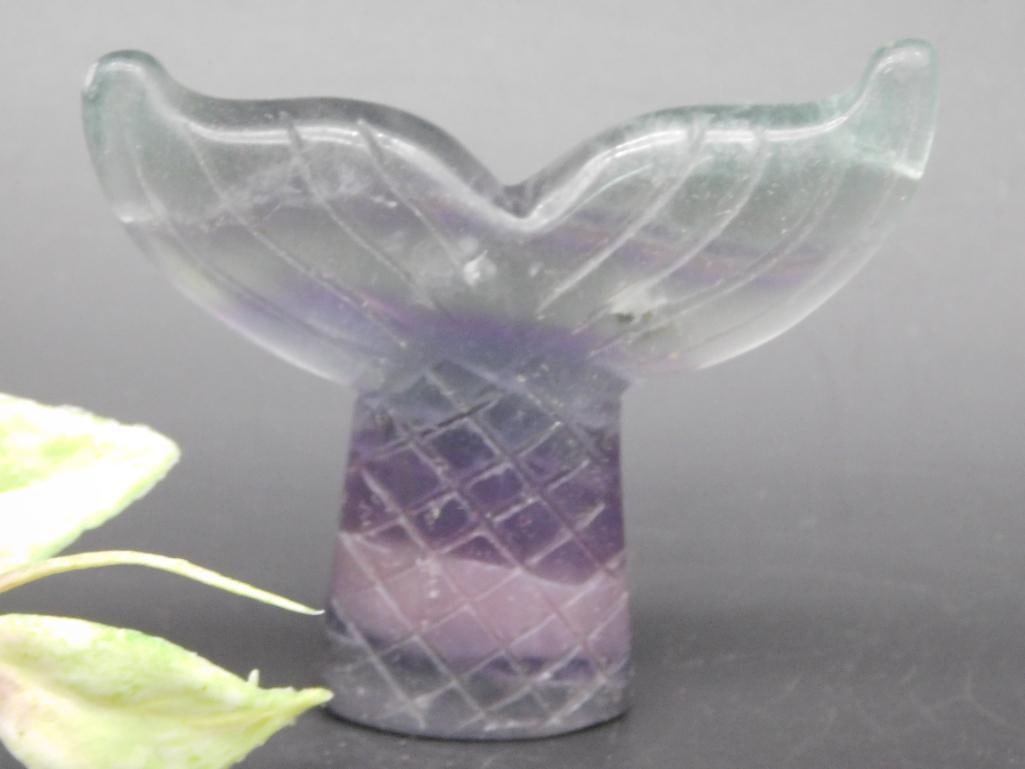 Carved Fluorite Whale Tail Sculpture: Carved fluorite sculpture in the shape of a whale tail with distinctive striations and colors. Features intricate detailing on the tail and a textured base. Compact size, as shown alongside a ruler fo