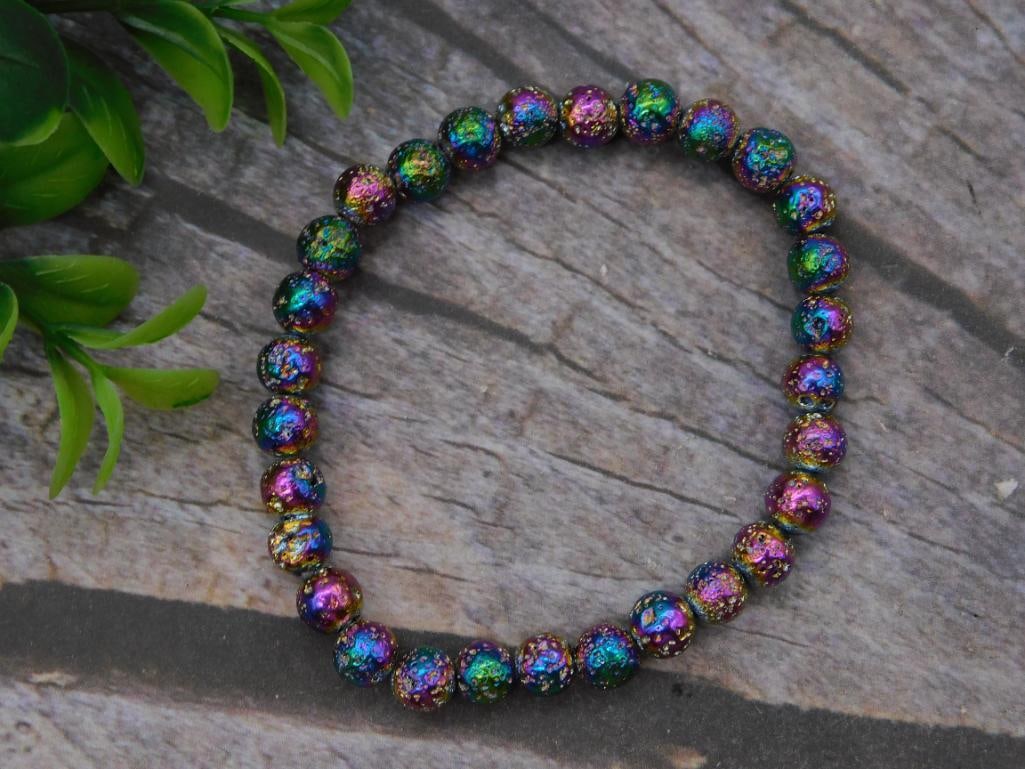 Rainbow Titanium Coated Bead Stretch Bracelet: A stretch bracelet strung with round beads featuring an iridescent rainbow coated finish that shifts color in the light. Sized to fit a standard wrist. A fun, colorful accessory piece.