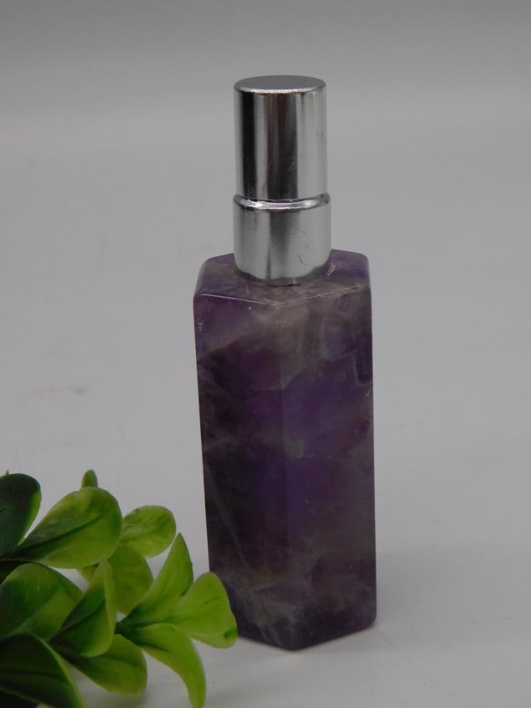 Carved Amethyst Crystal Perfume Spray Bottle: A perfume atomizer bottle carved from natural amethyst crystal with a silver tone spray top and cap. Stands approximately 4 inches tall. A pretty vanity piece combining natural crystal with a