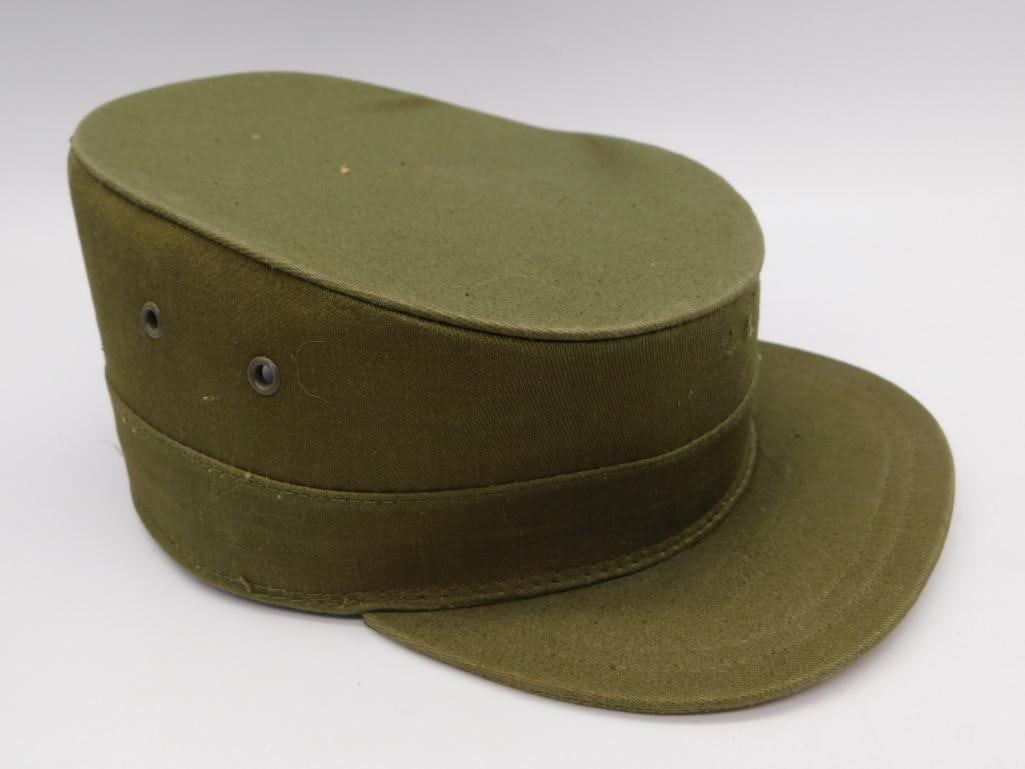 Vintage Olive Drab Military Field Cap: An olive-green cotton twill military-style field cap with a stiff rounded crown, front visor, and two metal eyelet vents on the side. Shown with a Westcott 12-inch ruler for scale, the cap measures