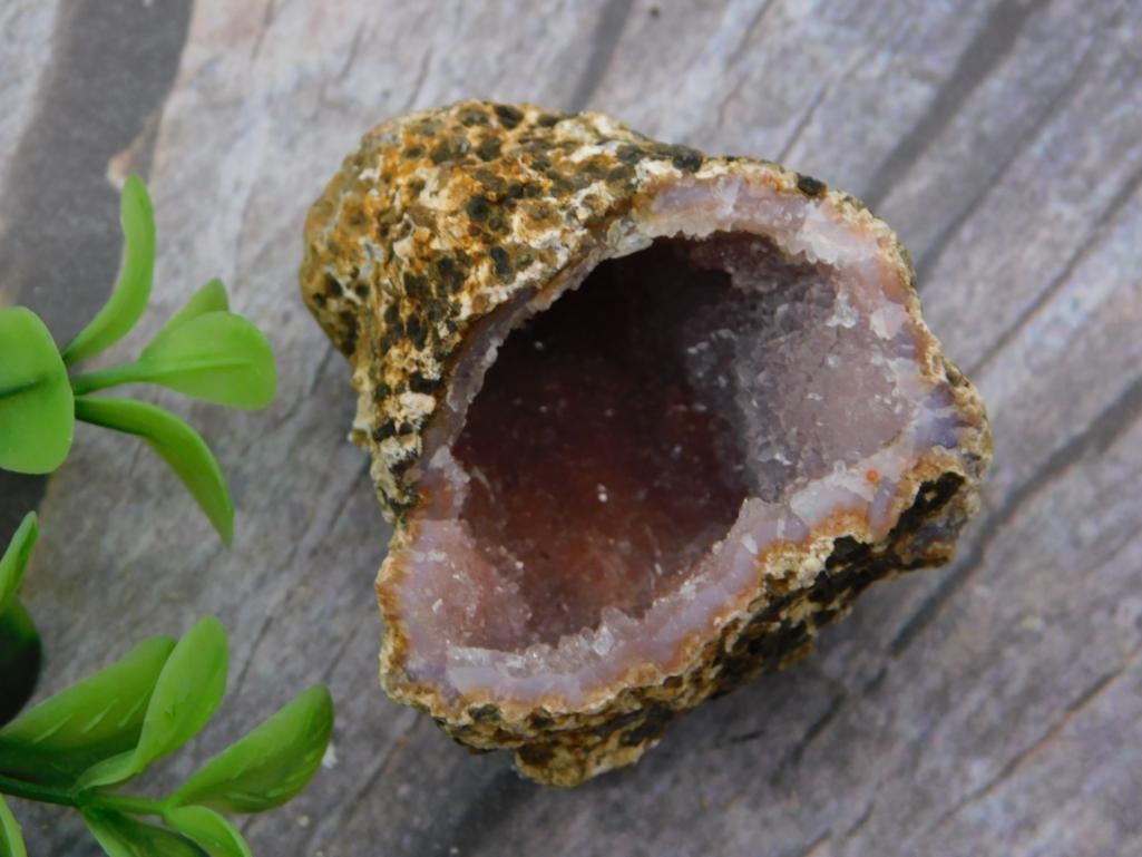 Natural Agate-Lined Geode Specimen with Druzy Crystal Interior: A hollow geode specimen split to reveal a pink and white druzy quartz-lined interior beneath a dark, mottled exterior crust. Auction tag lists weight at 52 grams. Measures roughly 3 inches, shown with