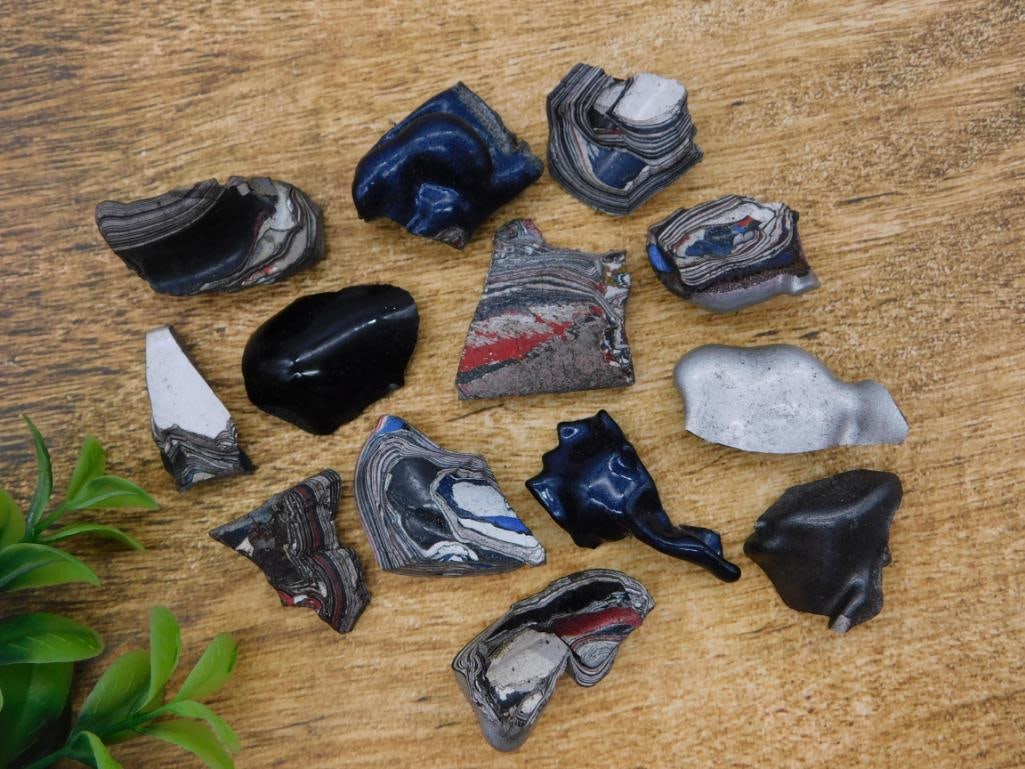 Fordite (Detroit Agate) Layered Paint Slag Specimens, Lot of 12+: A large collection of Fordite (automotive paint slag/"Detroit agate") pieces showing colorful layered striations in blue, red, black, and white from decades of baked automotive paint. Auction tag