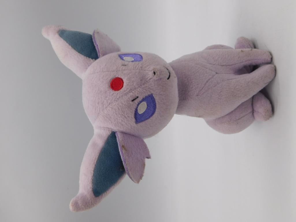 Espeon Pokemon Plush Stuffed Animal Toy: A soft plush Espeon figure with purple fur, blue-lined ears, embroidered red gem forehead marking and purple eyes. Shows light surface soiling from age/play. Measures approximately 8 inches long per t