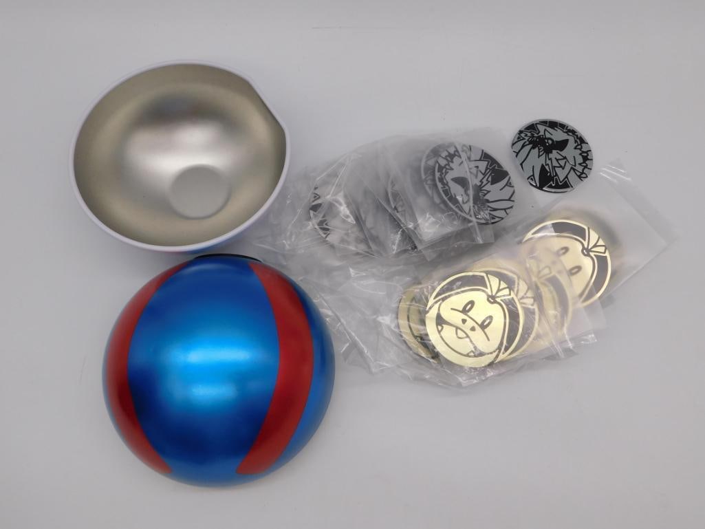 Pokemon Great Ball Roleplay Toy with Collectible Coins & Stickers: A large opening Great Ball-style roleplay toy (blue and red with silver interior) paired with a set of gold and black Pokemon battle coin stickers in original packaging. Ball measures approximately 4