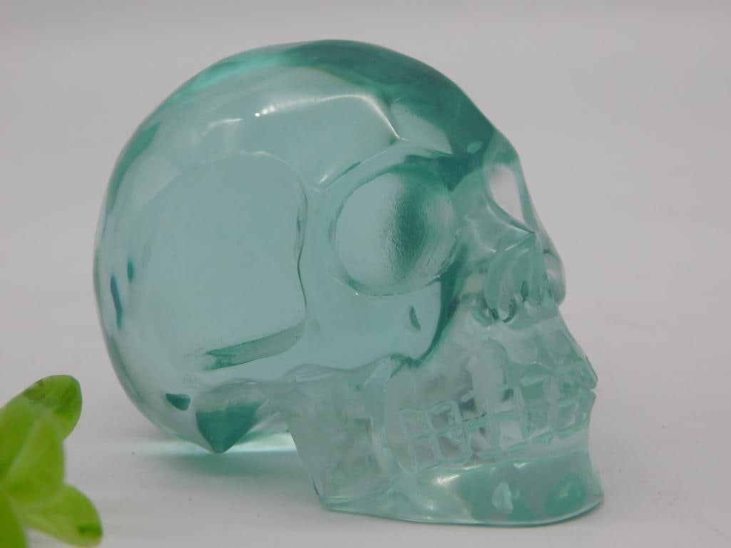 Carved Aqua Glass/Crystal Skull Figurine: A translucent aqua-teal carved skull figurine with detailed eye sockets, nasal cavity, and teeth, in the style of collectible crystal skulls. Auction tag lists weight at 278 grams. Measures