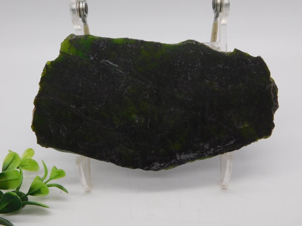 Rough Green GREEN OPAL Jade Slab: Large rough-cut slab of dark green mottled serpentine or nephrite jade with natural fractured edges, displayed on an acrylic stand. Measures approximately 6 inches wide. Unpolished natural stone speci
