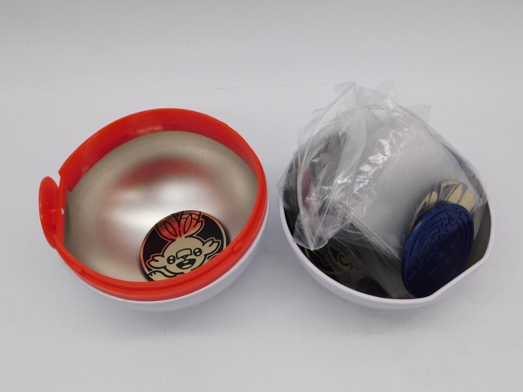 Pokemon Battle Coin Capsule Set, Large Poke Ball Container: Large white and red Poke Ball-style capsule toy that opens into two round bowls, each containing a collection of metal Pokemon battle coins featuring character artwork. Capsule measures approximately