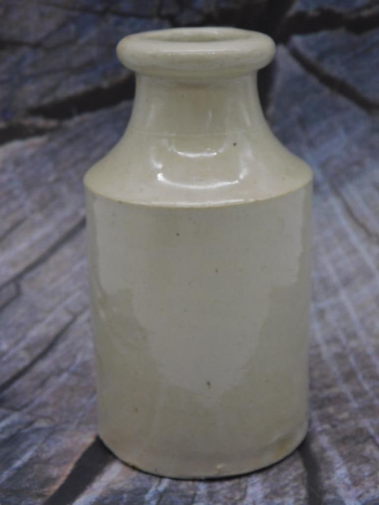 STONEWARE BEER BOTTLE: A cream-glazed salt-glazed stoneware bottle/jar with a flared collar neck, approximately 5-6 inches tall. Smooth pottery finish with minor surface speckling, shown with a ruler for scale.