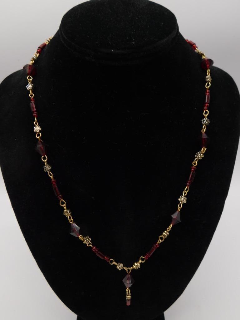 Red Crystal Bead Gold-Tone Necklace: A gold-tone chain necklace featuring faceted deep red glass beads with small flower-shaped rhinestone spacers and a red teardrop drop.