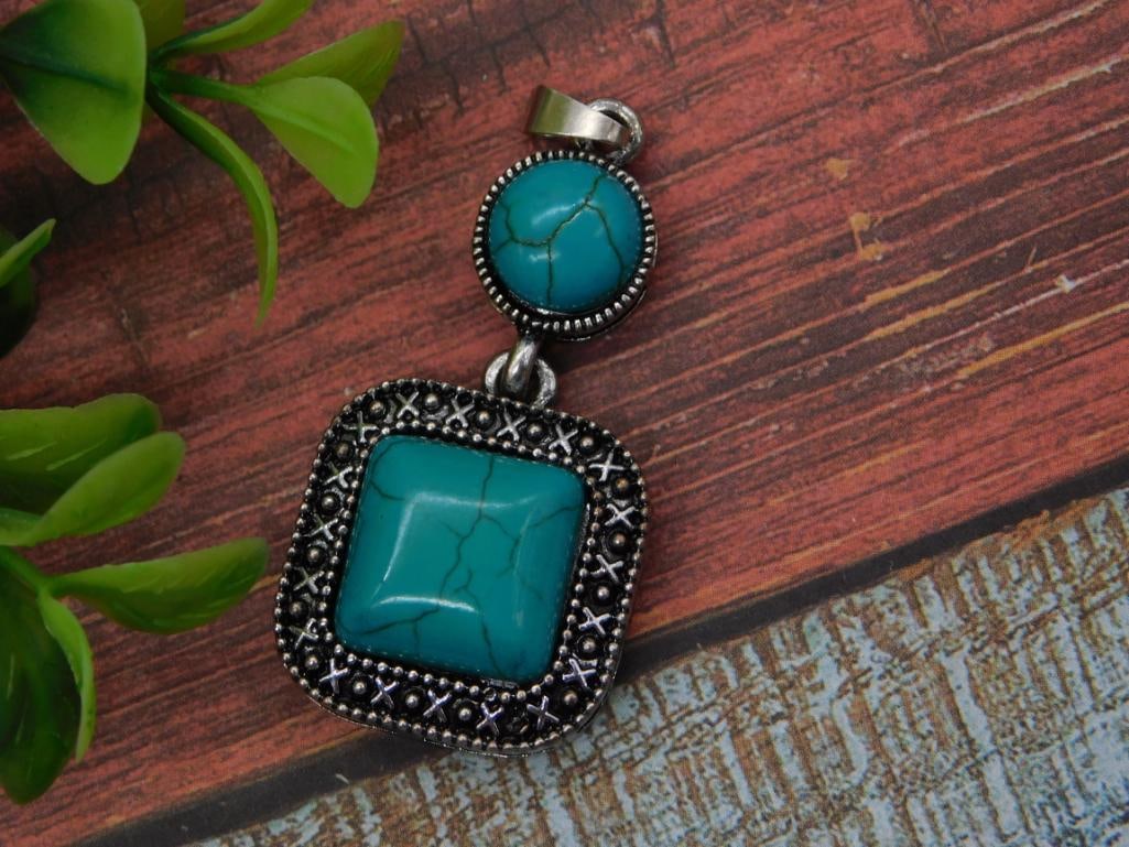 Silver-Tone Turquoise Pendant: A silver-tone pendant featuring a round turquoise cabochon accent above a larger square turquoise cabochon in an ornate beaded bezel.