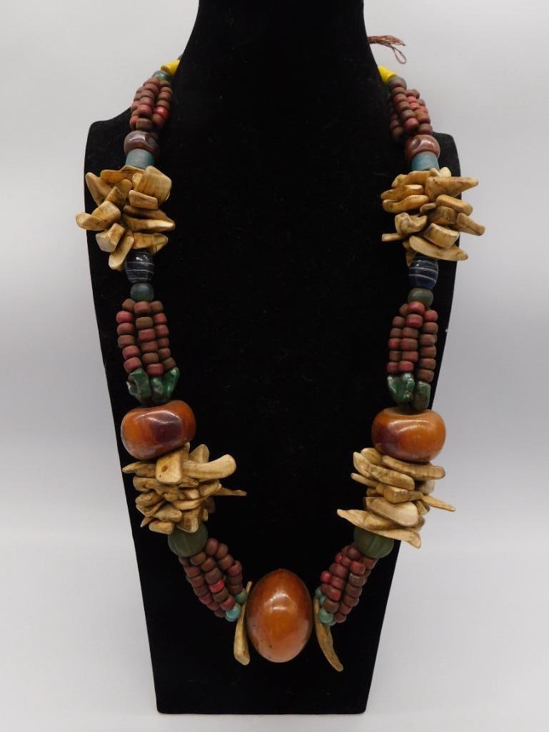 Tribal Style Wood and Bone Beaded Necklace: Necklace strung with carved wood beads, bone chip clusters, and amber-toned resin or bakelite beads in an earthy tribal design. Continuous strand, no visible metal clasp. Approximately 24-26 inches