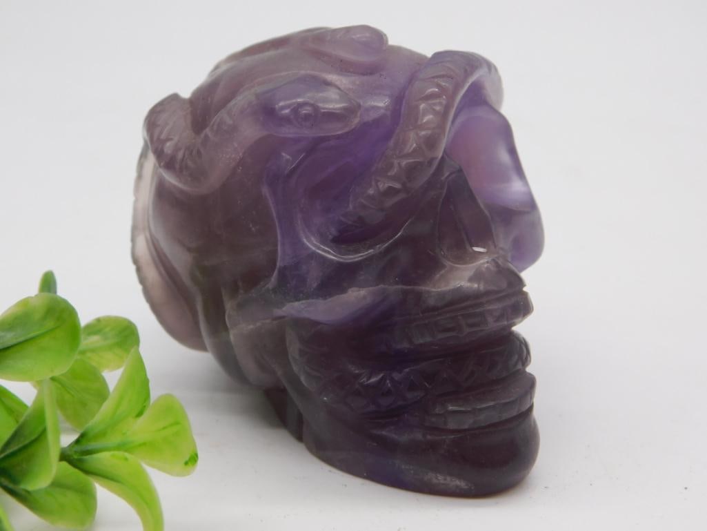Carved Amethyst Crystal Skull with Serpent Detail: Hand-carved amethyst crystal skull featuring intertwined snake carvings across the crown, 390 grams.