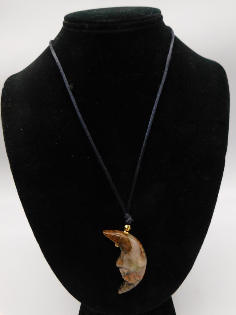 Carved Jasper Crescent Moon Pendant Necklace: Cord necklace with a carved crescent-moon-shaped jasper pendant in brown, orange, and cream tones, accented with a gold-tone bead.