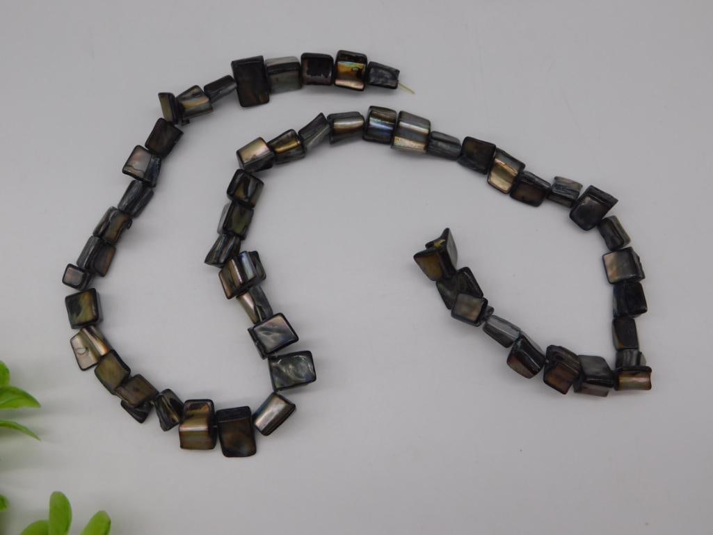 Black Mother of Pearl Shell Square Bead Necklace: Long strand necklace of iridescent black mother-of-pearl square-cut shell beads.