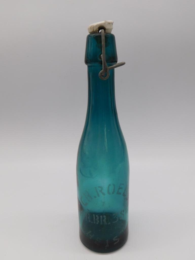 Antique Blue Glass Swing-Top Bottle: Antique teal blue glass bottle with wire bail porcelain swing-top stopper, embossed lettering.