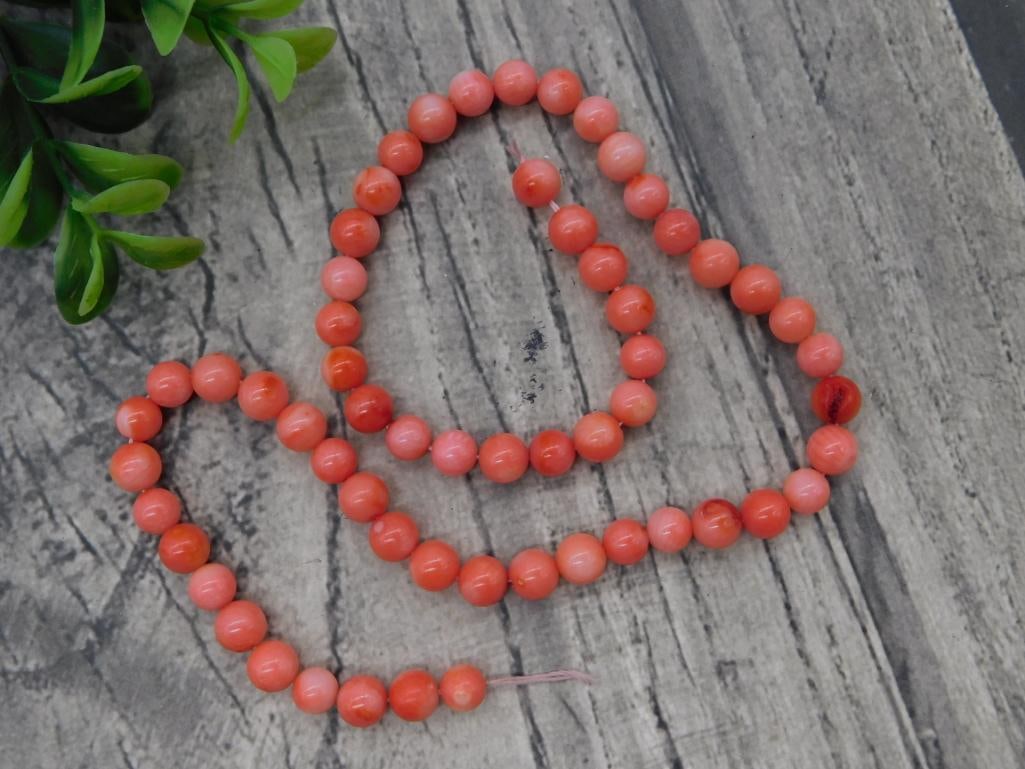 Pink Coral Bead Necklace: Long strand necklace of round pink coral-tone beads.